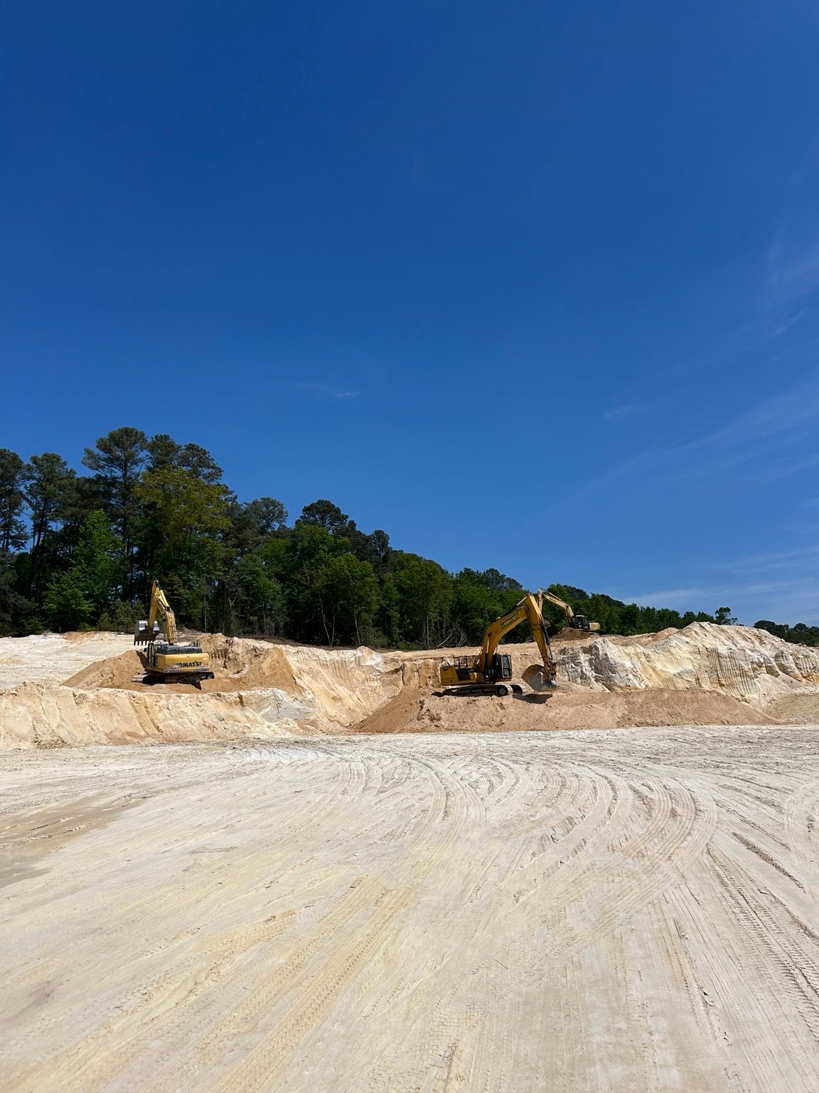 Wide view of multiple excavators working in the Pit 421 material area